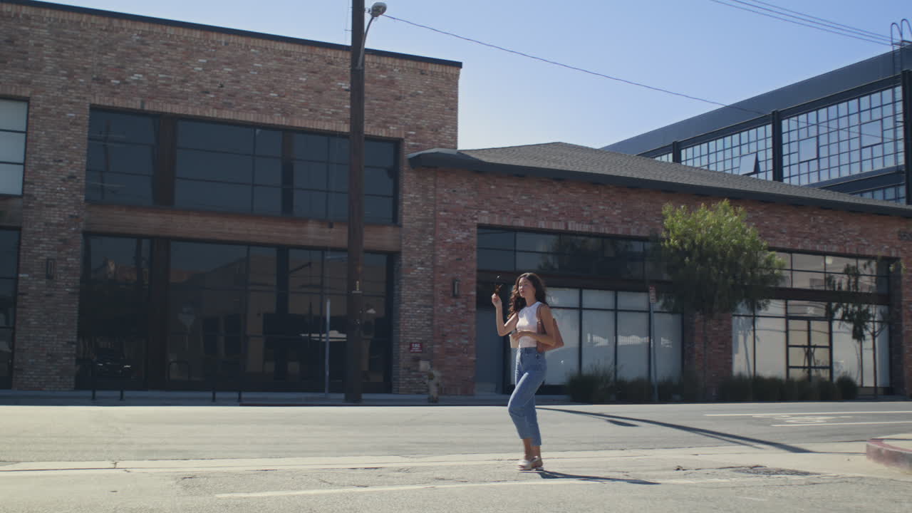 Mujer asiática cruzando la calle de la ciudad con una taza de café. Chica elegante con prisa hacia la oficina.
