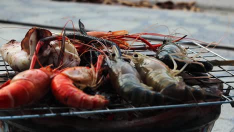 a side view of giant river prawns , some are already cooked and raw ones are put on the barbeque