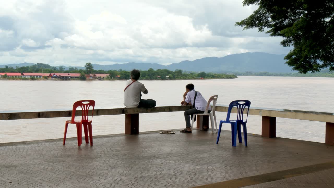 Locals rest beside the Mekong River in Thailand, looking across to Laos. A peaceful moment of daily life near the Thai-Laos border, captured in Chiang Khong