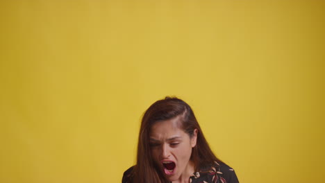 fotografía de estudio de una mujer emocionada con un teléfono móvil celebrando la ganancia de dinero contra un fondo amarillo 1