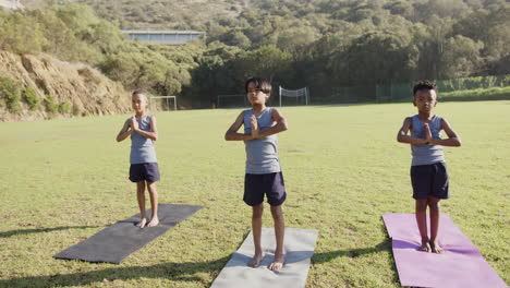practicing yoga on mats, three kids exercising outdoors at school field