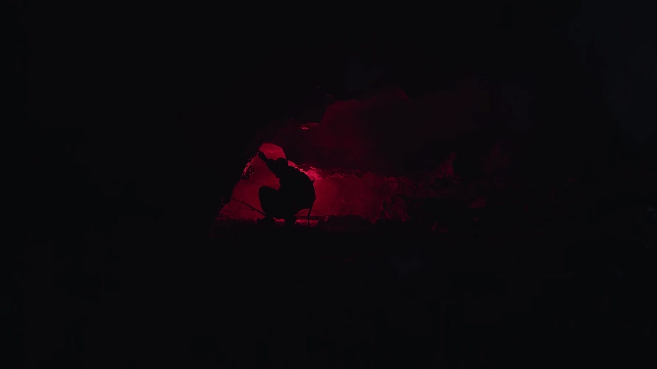 hombre explorando una cueva por la noche con luz roja