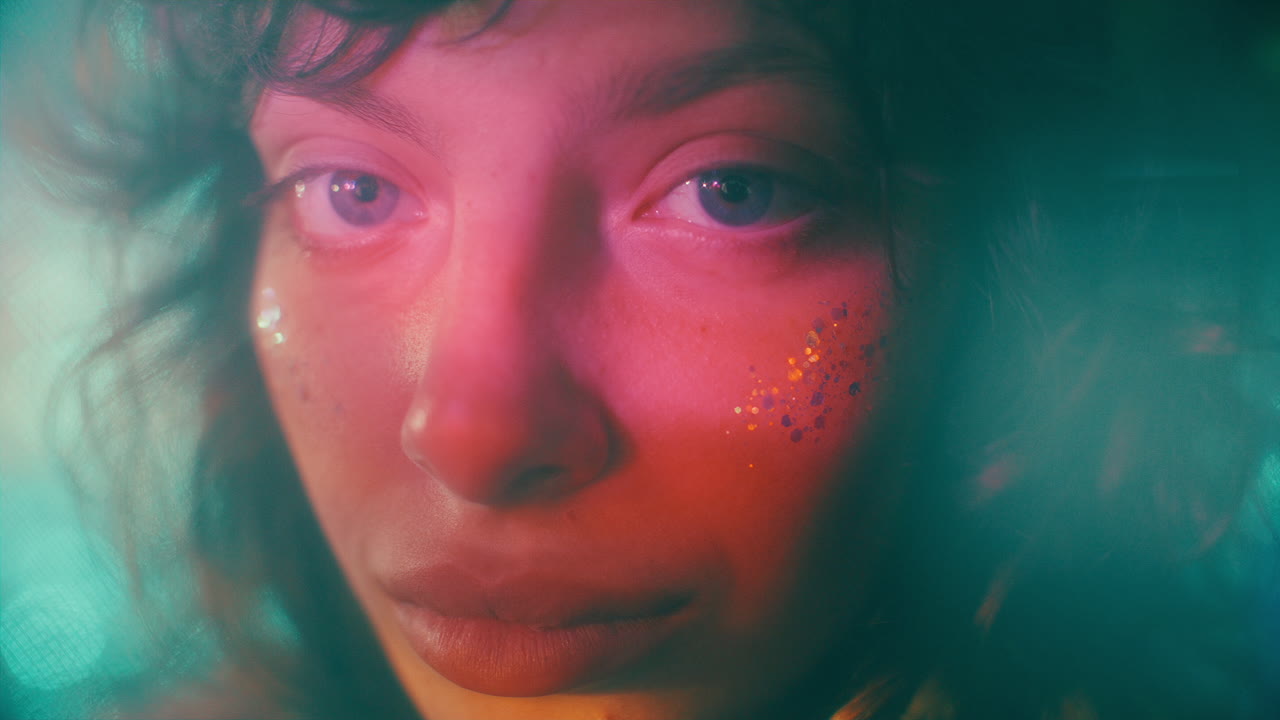 Close Up of Attractive Woman with Glitter on Cheeks in Multicolored Lights