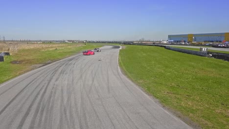 coches de deriva aérea que pasan por una pista de carreras, coche rojo y marrón con patines de neumáticos y hierba verde