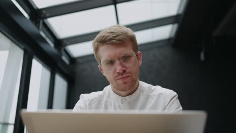 businessman is examining report on laptop screen in office working alone and thinking about developing company