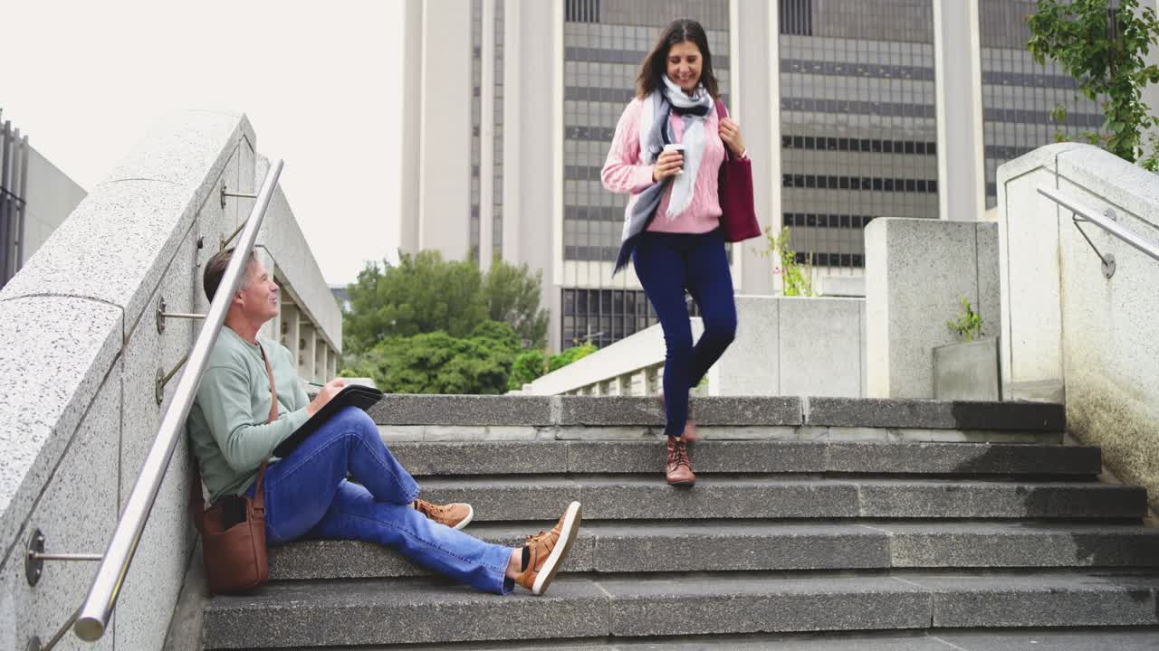 Man writing on stairs beside coffee cup glancing at passing woman with red tote, copy space