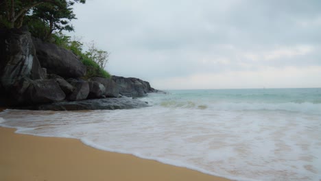cinematic shot of sea waves breaking on the rocks and sandy beach of con dao island