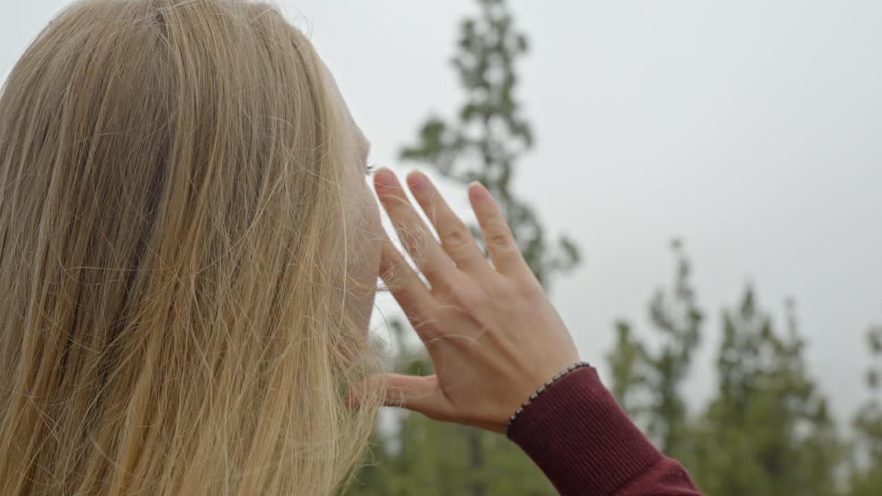 멀리서 소리치는 여성 관광객의 클로즈업: 숲과 바다