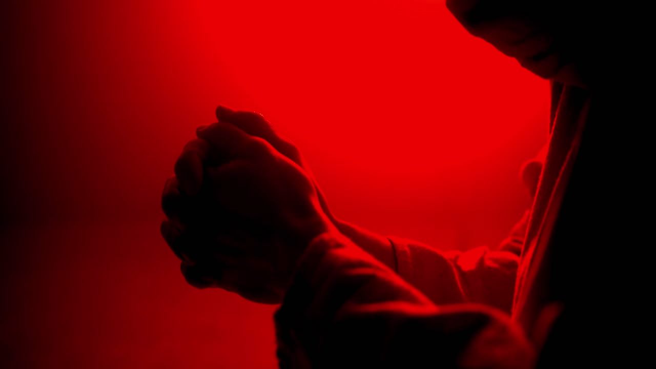 Closeup of Jesus Christ folding hands praying. Christianity, Easter visual, bible scene or temptation, prayer, worship visual.