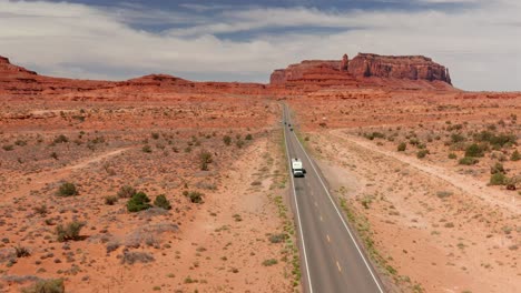 aerial view of a truck towing a camper on a long two lane highway in utah