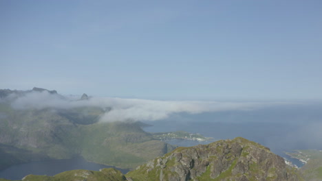 Aerial-view,-flying-past-Lofoten-mountain-peak-through-clouds