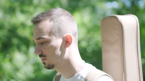 young man walking with guitar on street near forest