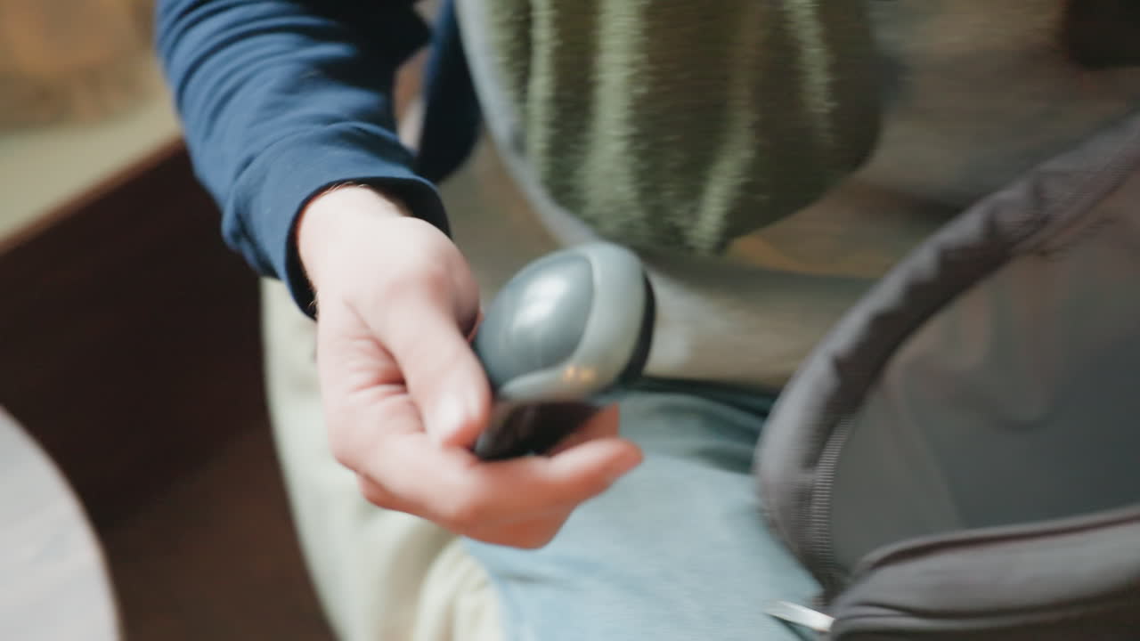 Mano abriendo la cremallera de la bolsa del portátil sacando un ratón inalámbrico, colocando el dispositivo en una mesa de madera junto a un bloc de notas y una vela, primer plano detallado del movimiento, colocación cuidadosa para un flujo de trabajo ergonómico, tonos cálidos