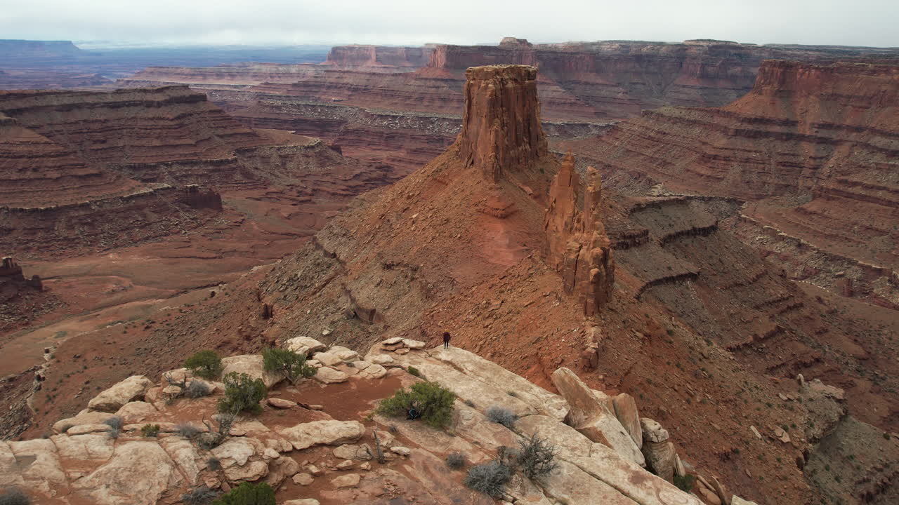 Ripresa con drone di una persona che corre sulla cima di una collina di arenaria con una vista mozzafiato sul deserto dello Utah, sui Parchi Nazionali di Canyonlands e Dead Horse.