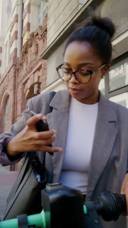 woman using a smartphone on an e-scooter in a city street