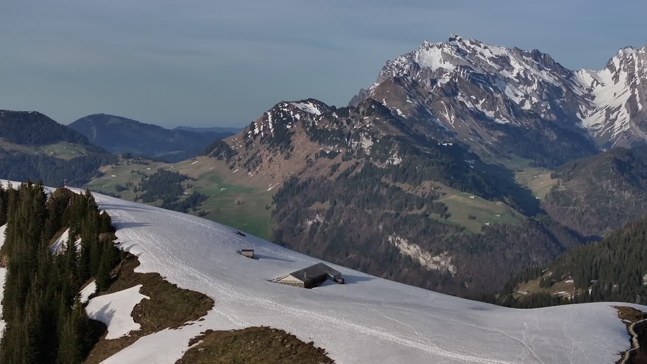 vista aérea de casas casi medio enterradas en la nieve en la estación de esquí de amden, con la gigante e imponente montaña säntis en el fondo
