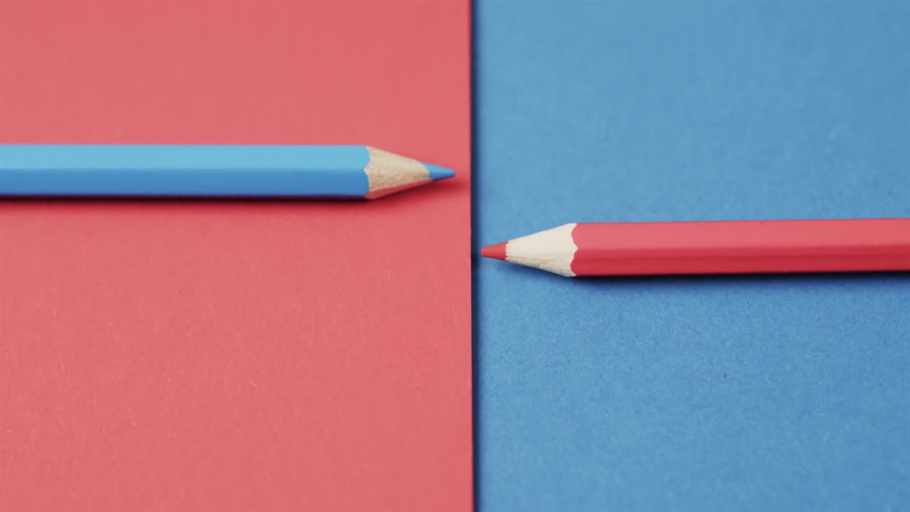 Overhead view of blue and red crayons arranged on red and blue background, in slow motion