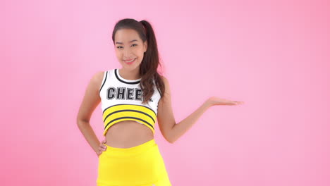 a cheerleader dressed in yellow and black team colors gestures with her hand palm up to the copy space to her left