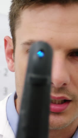primer plano del optometrista mirando a través del oftalmoscopio