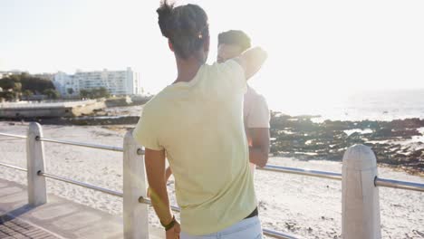 feliz pareja masculina gay diversa bailando en el paseo marítimo, cámara lenta