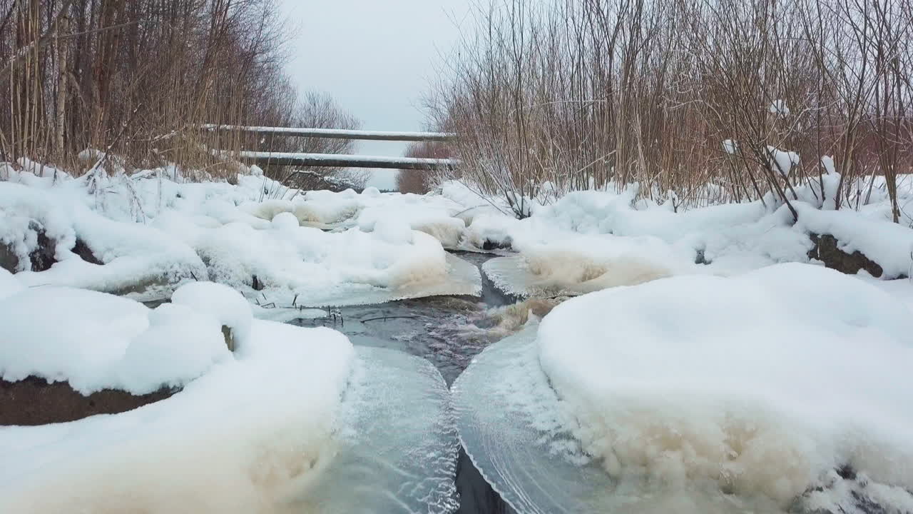 무인 항공기 틸트 업 샷에서 얼어 붙은 숲을 통해 야생 숲 강 급류