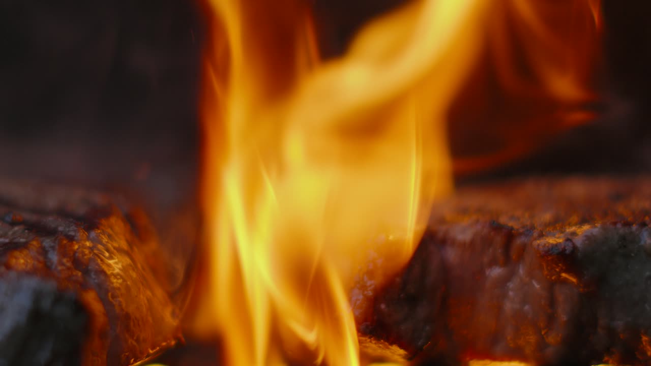 Fiamme del barbecue che cuociono una succulenta bistecca di controfiletto di manzo britannico con fuoco e fumo al rallentatore