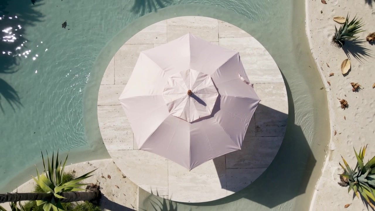 Sunlight and breeze causing pink umbrella casting shifting shadow on round deck, ripples moving
