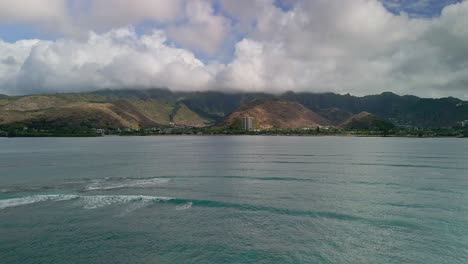 aerial view of hawaiian coastline with mountains and clouds