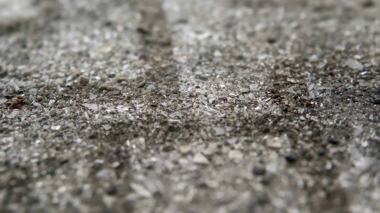 Racking low camera shifting focus over textured pavement, revealing central groove and pebbles