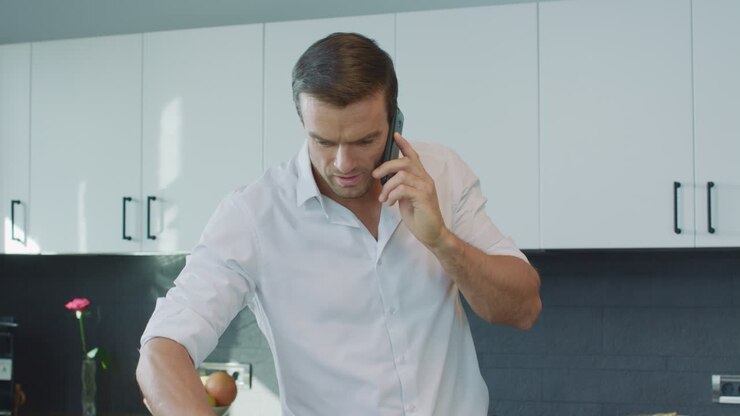 Uomo sorridente che parla al telefono in una cucina di lusso
