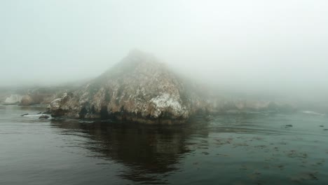 fly over the ocean with epic cliff side in california coastline on a foggy day