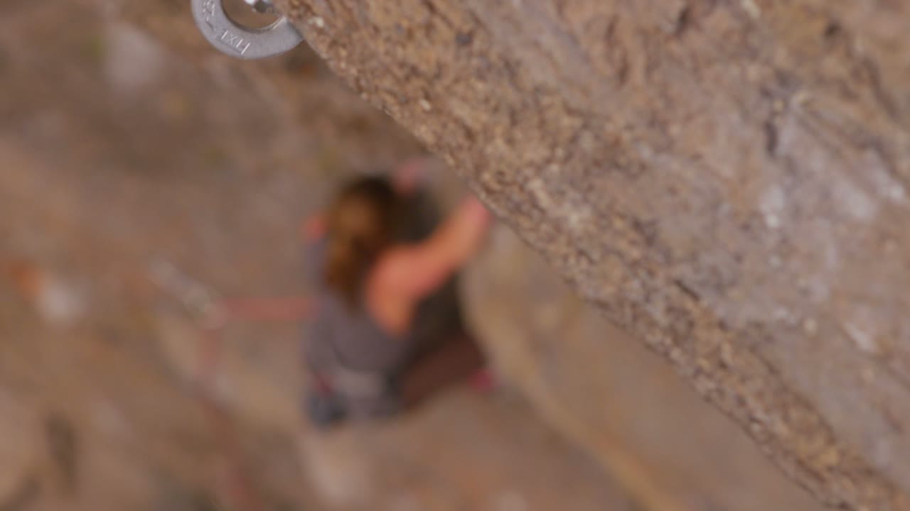 vista de ángulo alto mirando hacia abajo a un escalador escalando una pared de roca pura