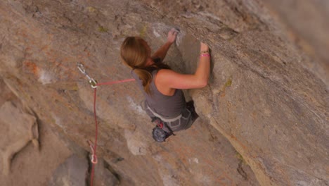 High-angle-view-looking-straight-down-at-a-rock-climber-scaling-a-sheer-rock-wall