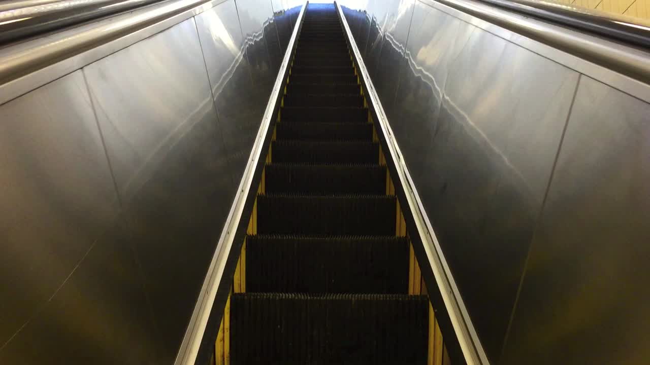 Pedestrian POV riding and looking upwards on an interior empty city escalator
