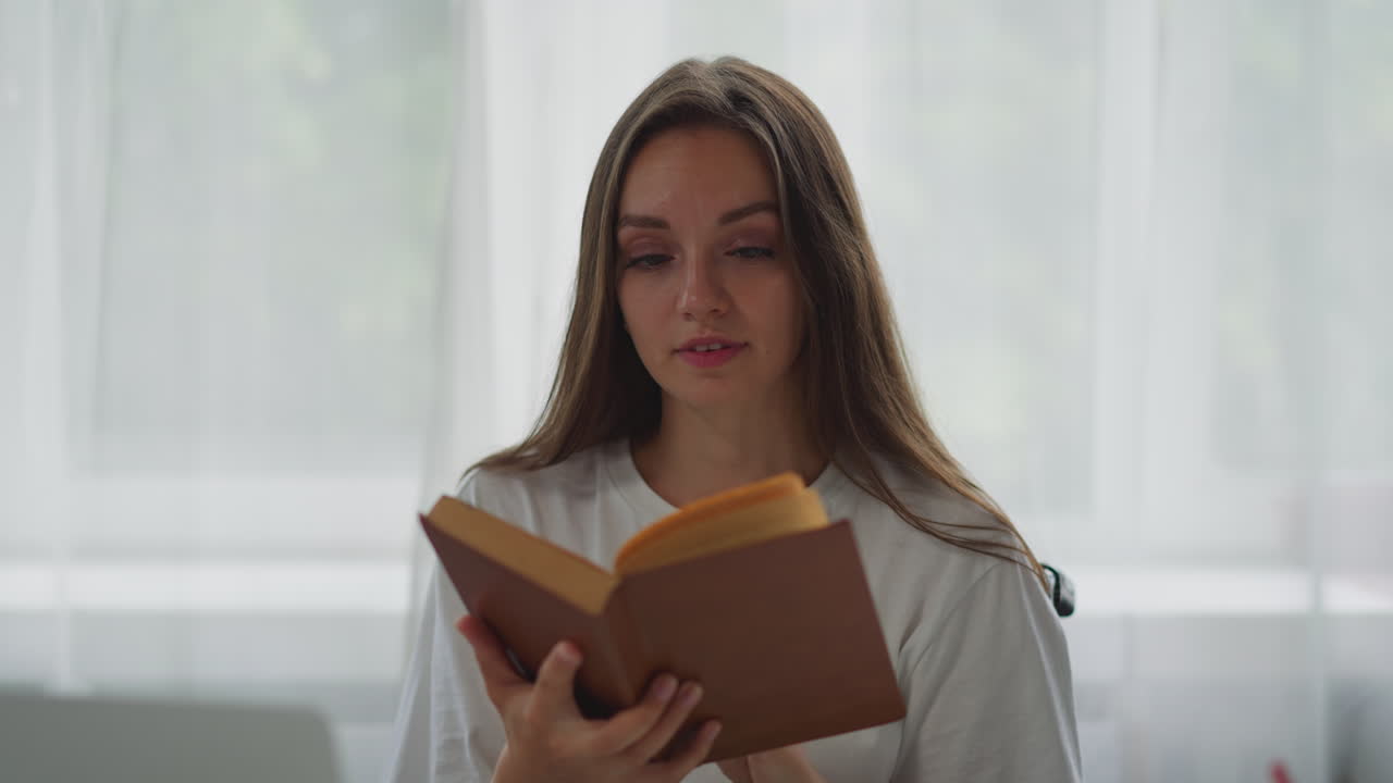 mujer centrada se sienta en silla de ruedas leyendo un libro interesante