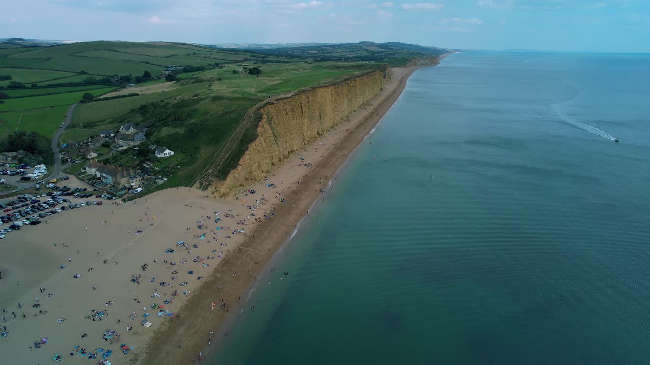Bridport West bay cliffs above British seaside turquoise ocean coastline aerial orbit right