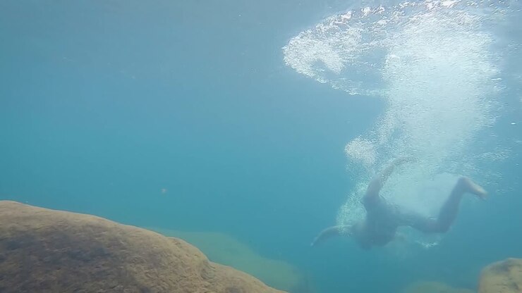 young man deep diving in clear blue water at day from different angle