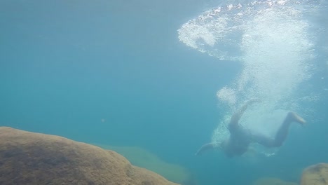 Junger-Mann-Taucht-Tagsüber-Aus-Einem-Anderen-Blickwinkel-Tief-In-Klares,-Blaues-Wasser