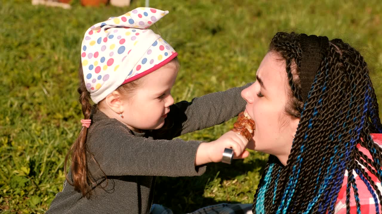 Una dolce figlioletta dà da mangiare alla mamma spiedini di carne shashlik nel cortile sul retro