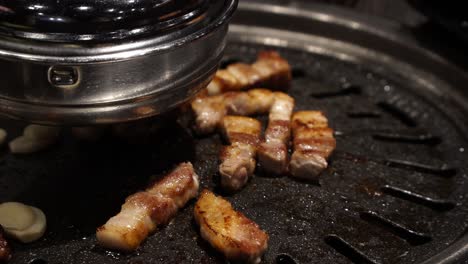 pork belly getting seared on traditional korean barbecue in restaurant