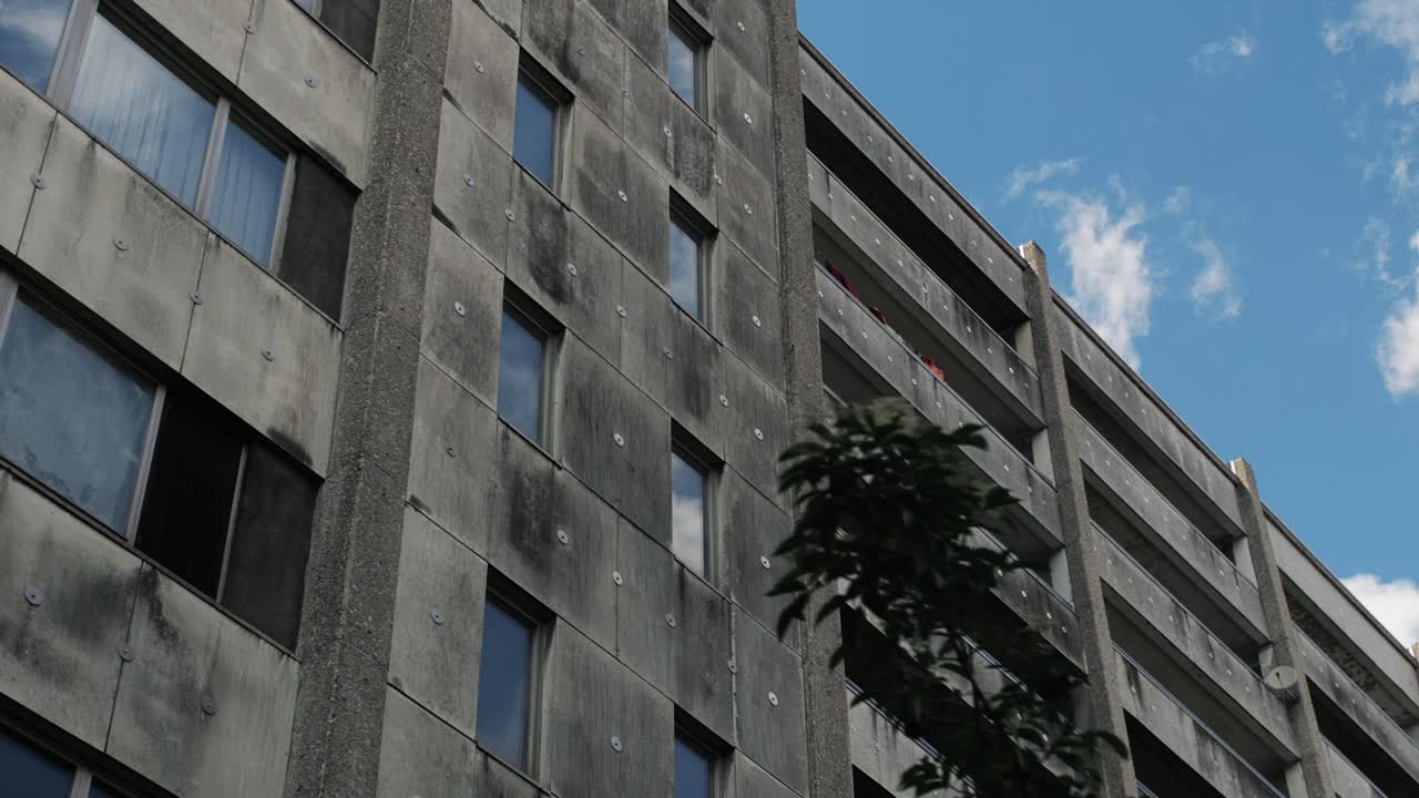Slow motion reveal of aged apartment blocks in a low-income residential area under a blue sky