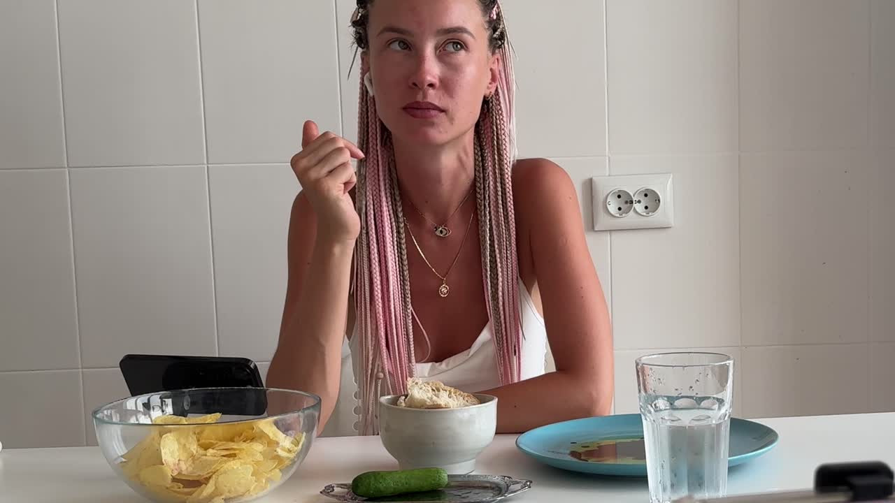 Mujer joven comiendo patatas fritas y viendo contenido