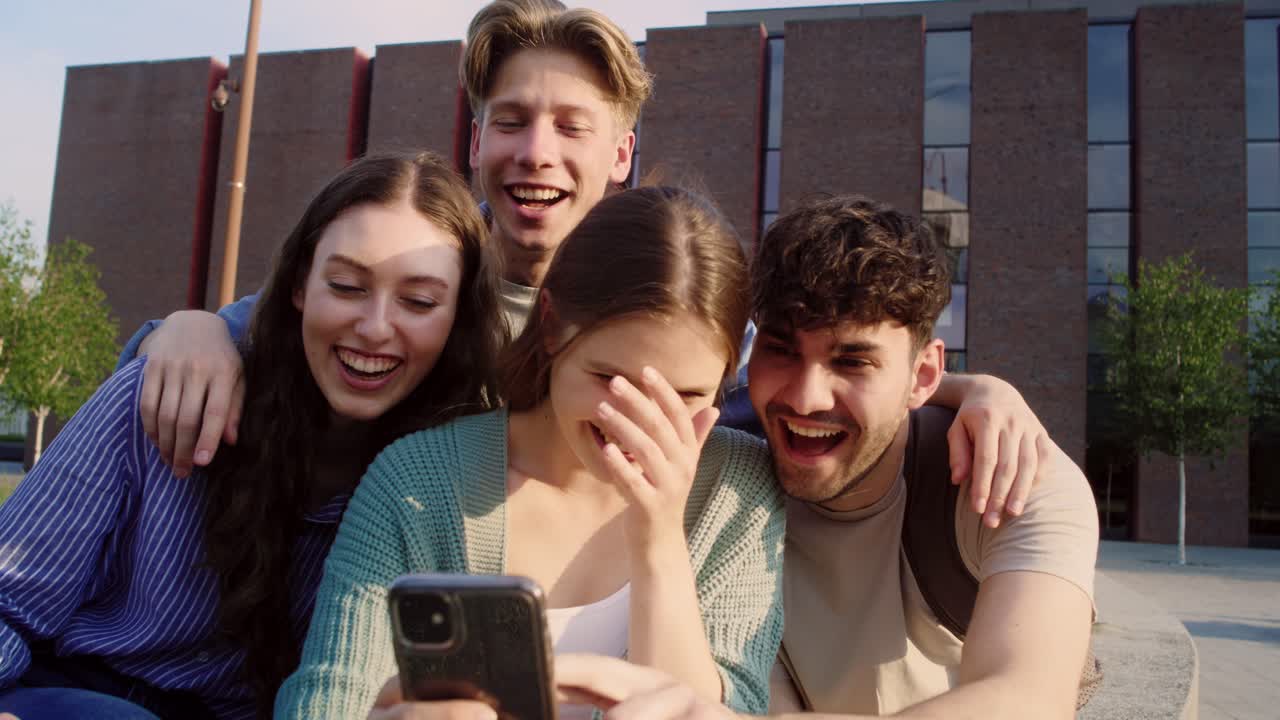 grupo de estudiantes caucásicos tomando selfies fuera del campus universitario