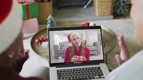 diversas amigas mayores que usan una computadora portátil para una videollamada de navidad con una mujer feliz en la pantalla