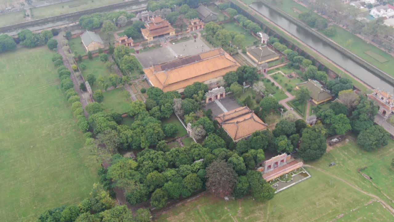 베트남의 무인기 공중 풍경: 흐린 안개의 날, 황제의 석 벽돌 요새 벽, 푸른 정원, 사원 및 운하를 날아다니고 있습니다.
