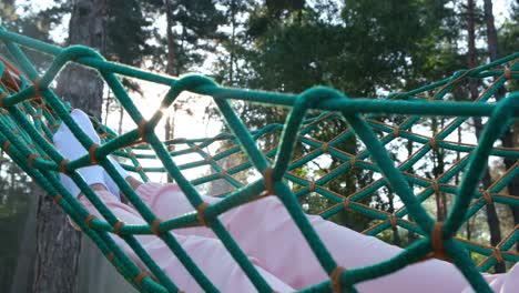 legs of a girl lying in a hammock in the woods young woman relaxes and rests in a hammock in the middle of the forest