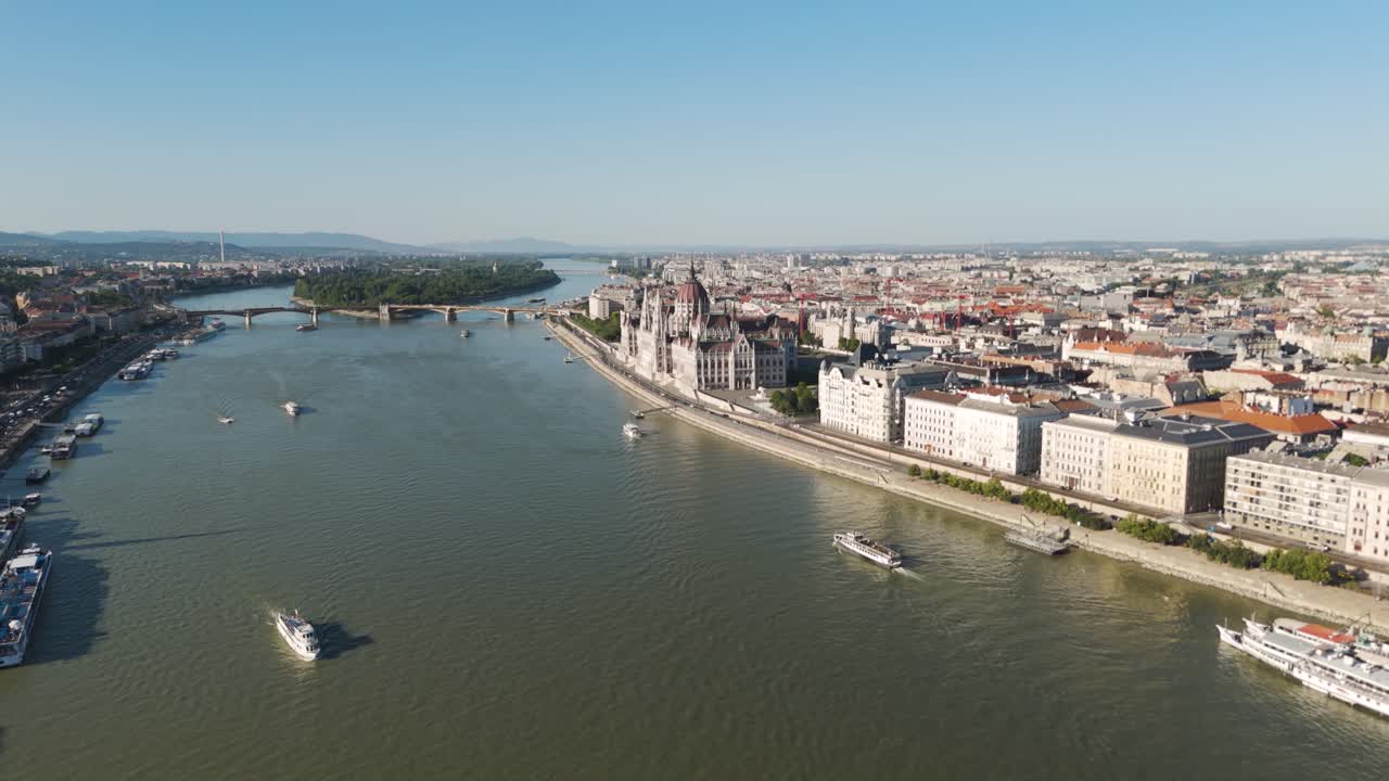 Drone flight over the Danube River leading to the Hungarian Parliament Building in Budapest, showing the historic architecture and riverfront views