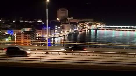 cars rush over queen juliana bridge at night, handelskade and queen emma bridge in view