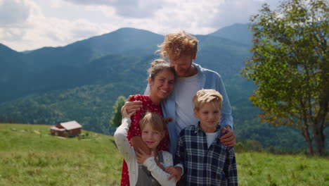 retrato de una familia feliz en las montañas de vacaciones de verano. una pareja abrazada con los niños.