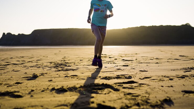 Ragazza che corre sulla spiaggia al tramonto